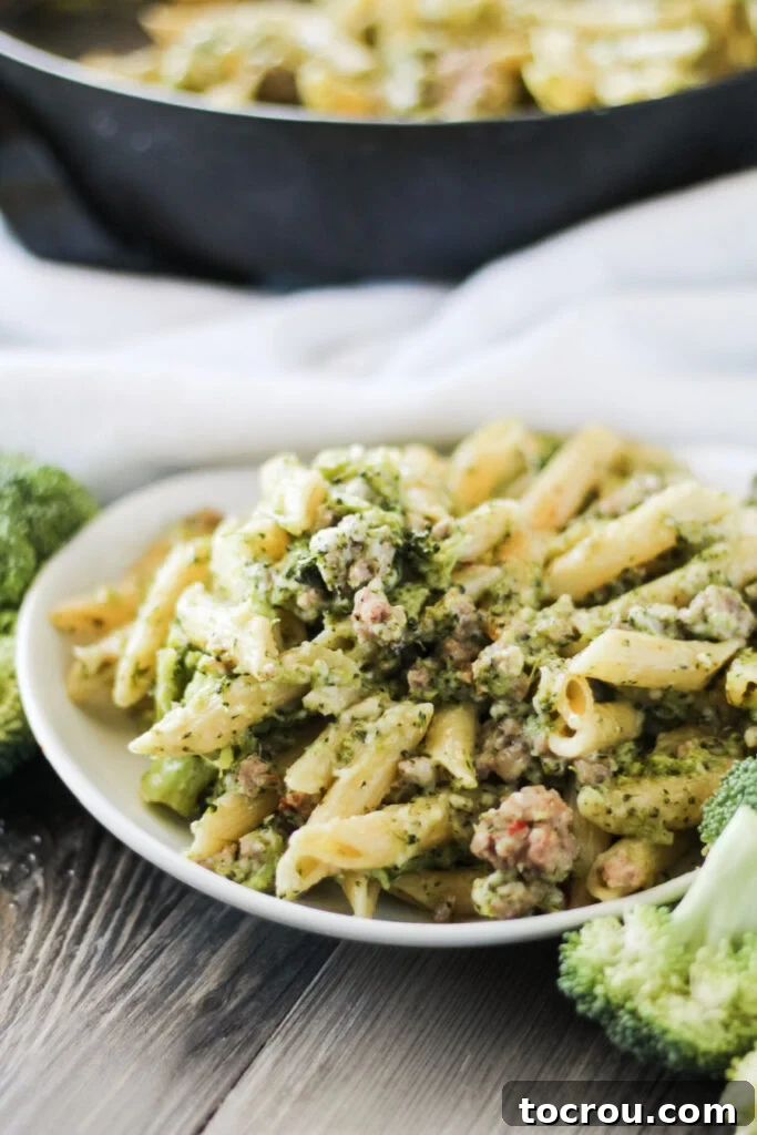 Close-up of a plate of one-pot sausage pasta in front of a large pot, ready to serve.